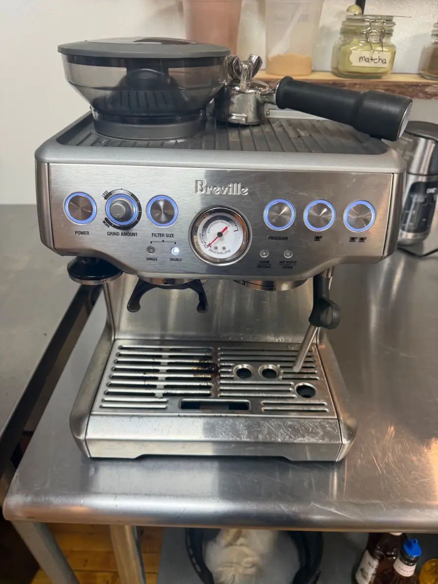 Breville espresso machine with portafilter and grinder on a stainless steel counter