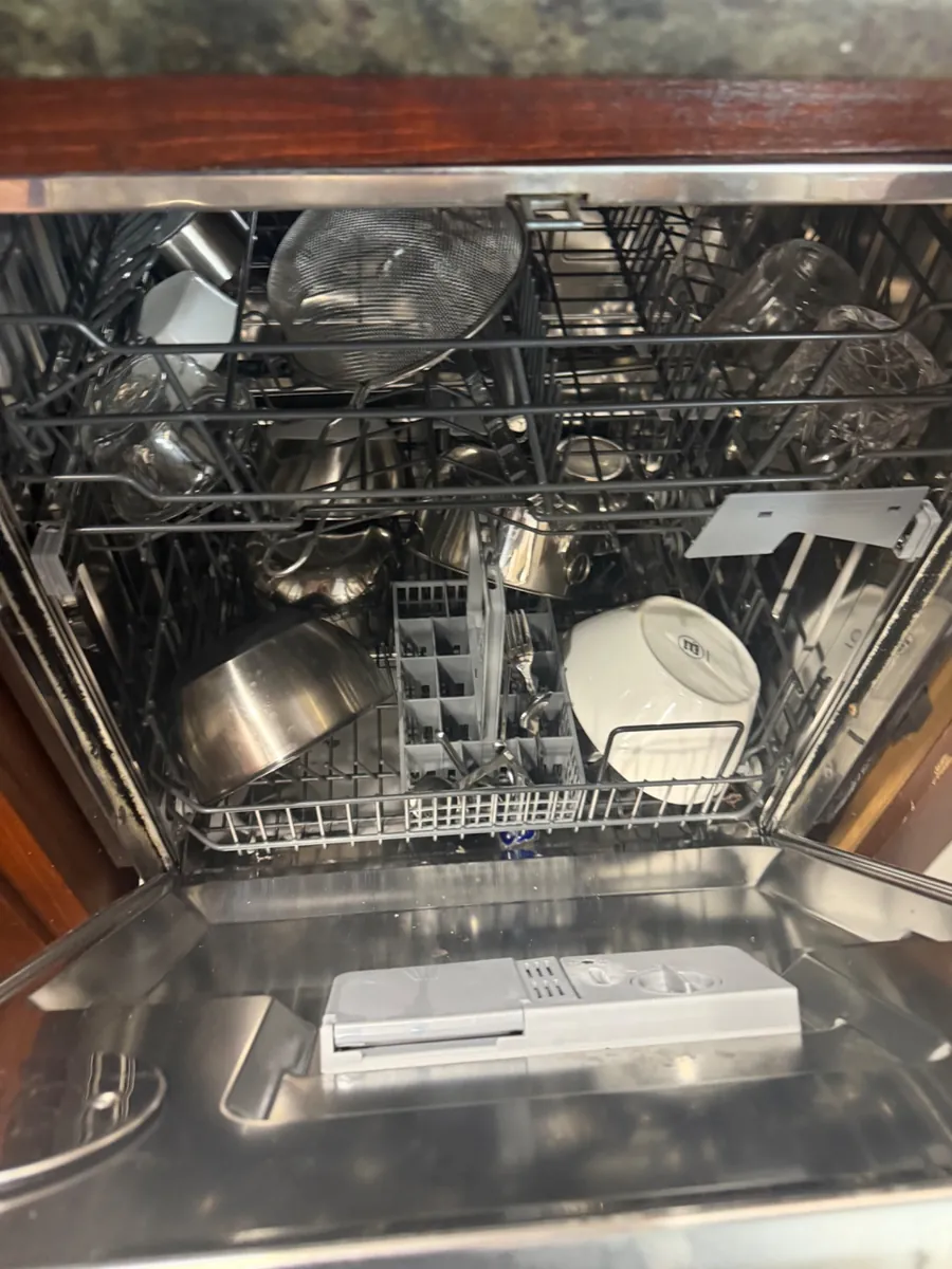Open dishwasher with loaded racks during a service visit