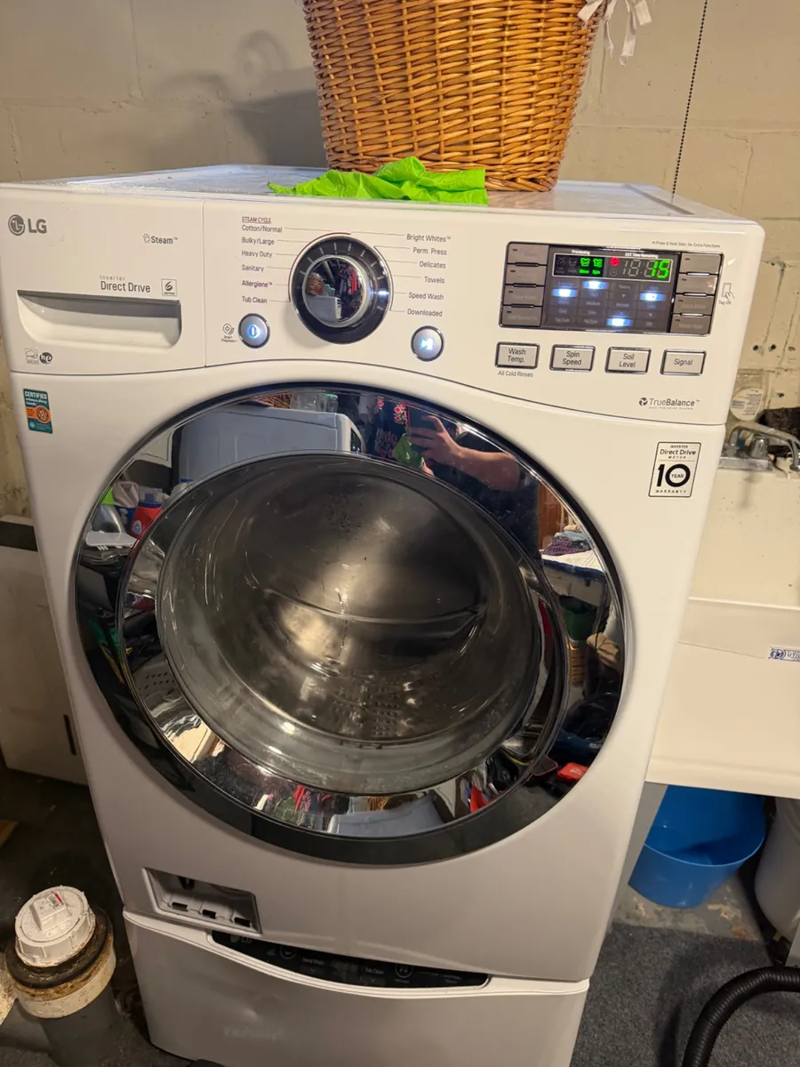 LG front-load washer on a pedestal in a basement laundry